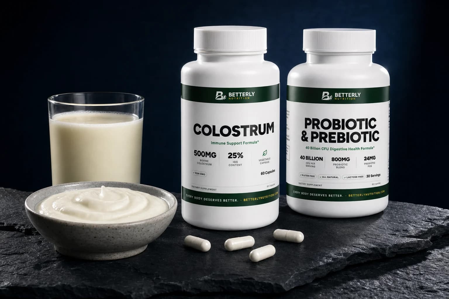 Colostrum and Probiotic & Prebiotic bottles side by side on dark slate beside a glass of milk, a bowl of yogurt and four capsules