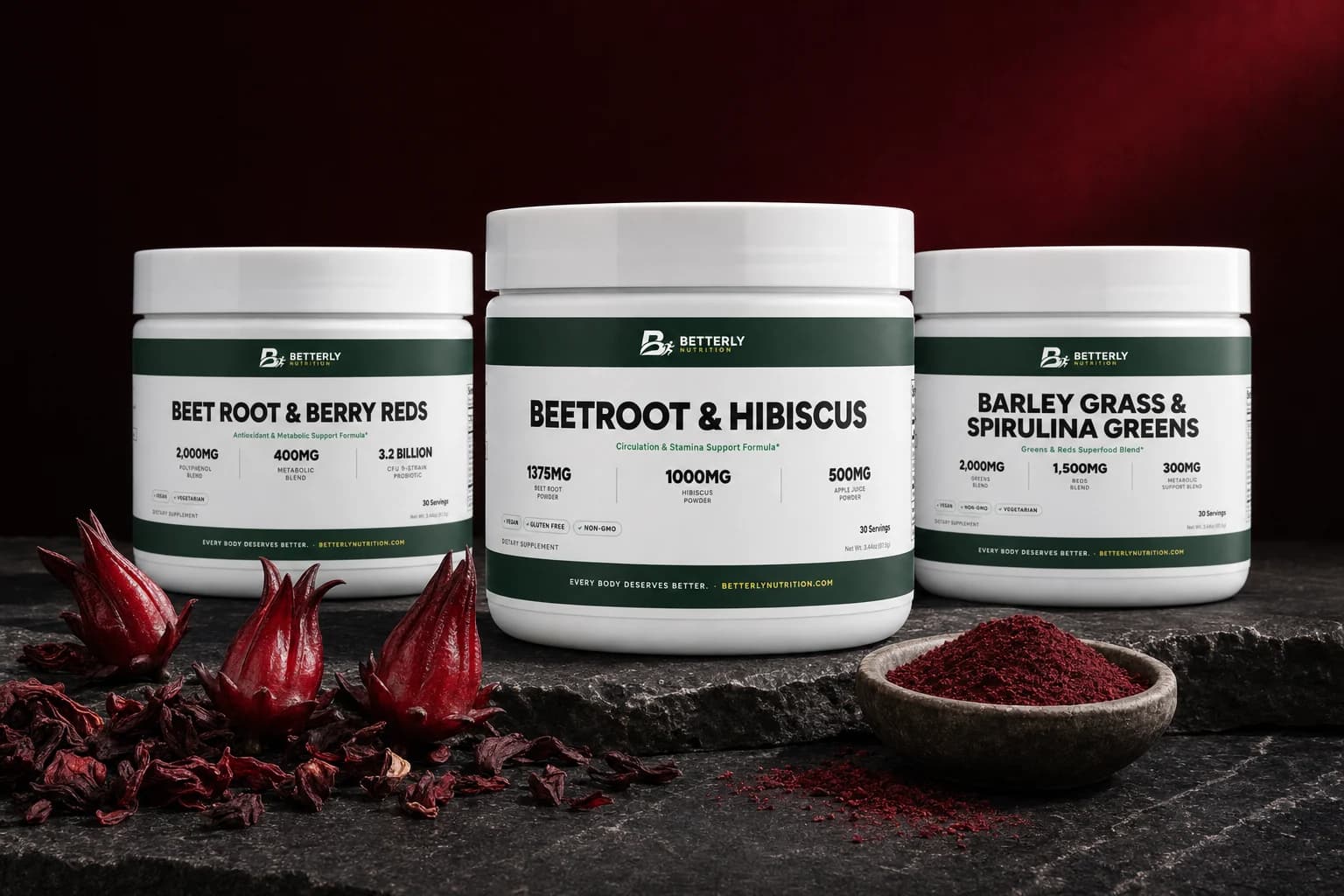 Beetroot & Hibiscus Powder tub between Reds and Greens powder tubs on dark stone, with fresh hibiscus calyces and a bowl of red powder