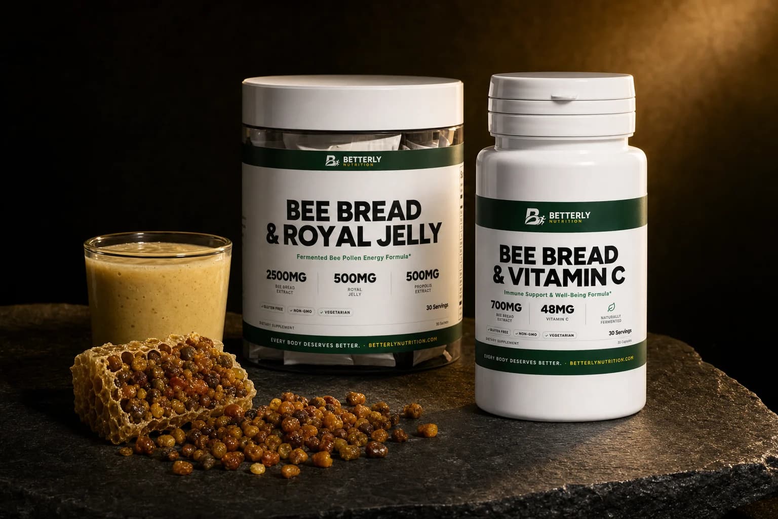 Bee Bread & Vitamin C bottle and a Bee Bread & Royal Jelly sachet tub on dark stone by a pale smoothie and comb heaped with bee bread