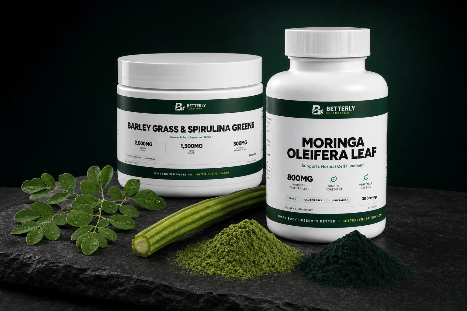 Moringa Oleifera Leaf bottle and Barley Grass & Spirulina Greens tub on dark slate beside a moringa sprig, cut pod and two green powders