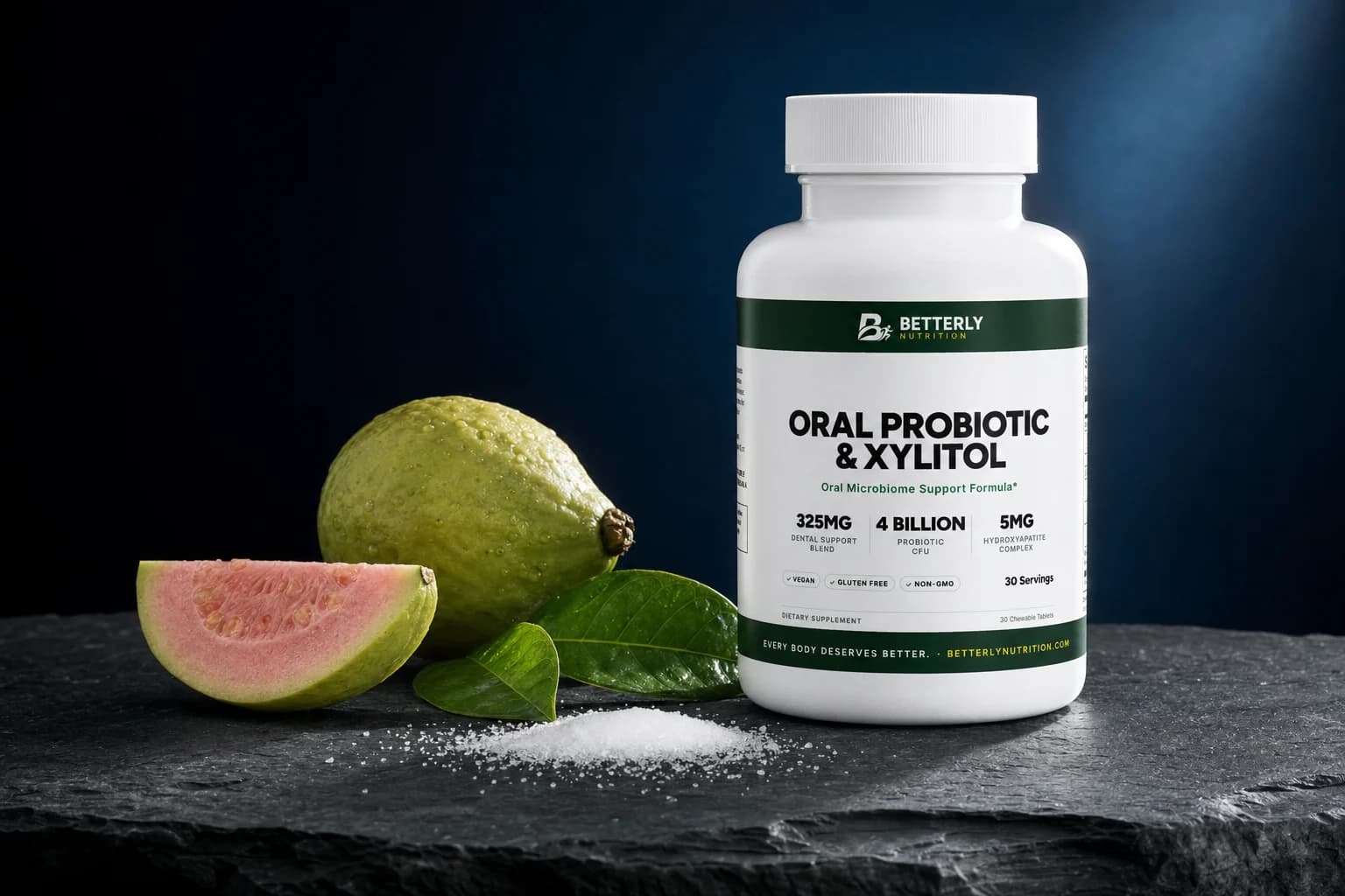 Oral Probiotic & Xylitol chewables bottle on dark slate with a whole guava, a pink guava wedge, two leaves and a mound of white crystals