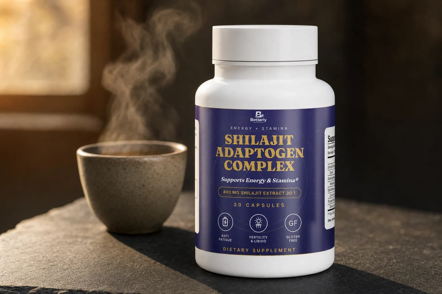 Betterly Shilajit Adaptogen Complex bottle on a dark slate counter beside a steaming cup of tea