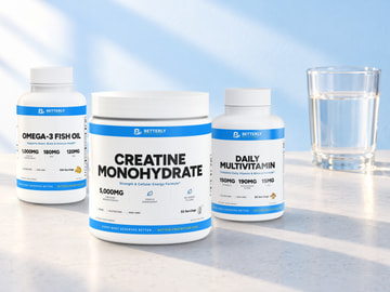 Daily Multivitamin Capsules, Omega-3 Fish Oil Softgels and Creatine Monohydrate Powder together on a sunlit counter